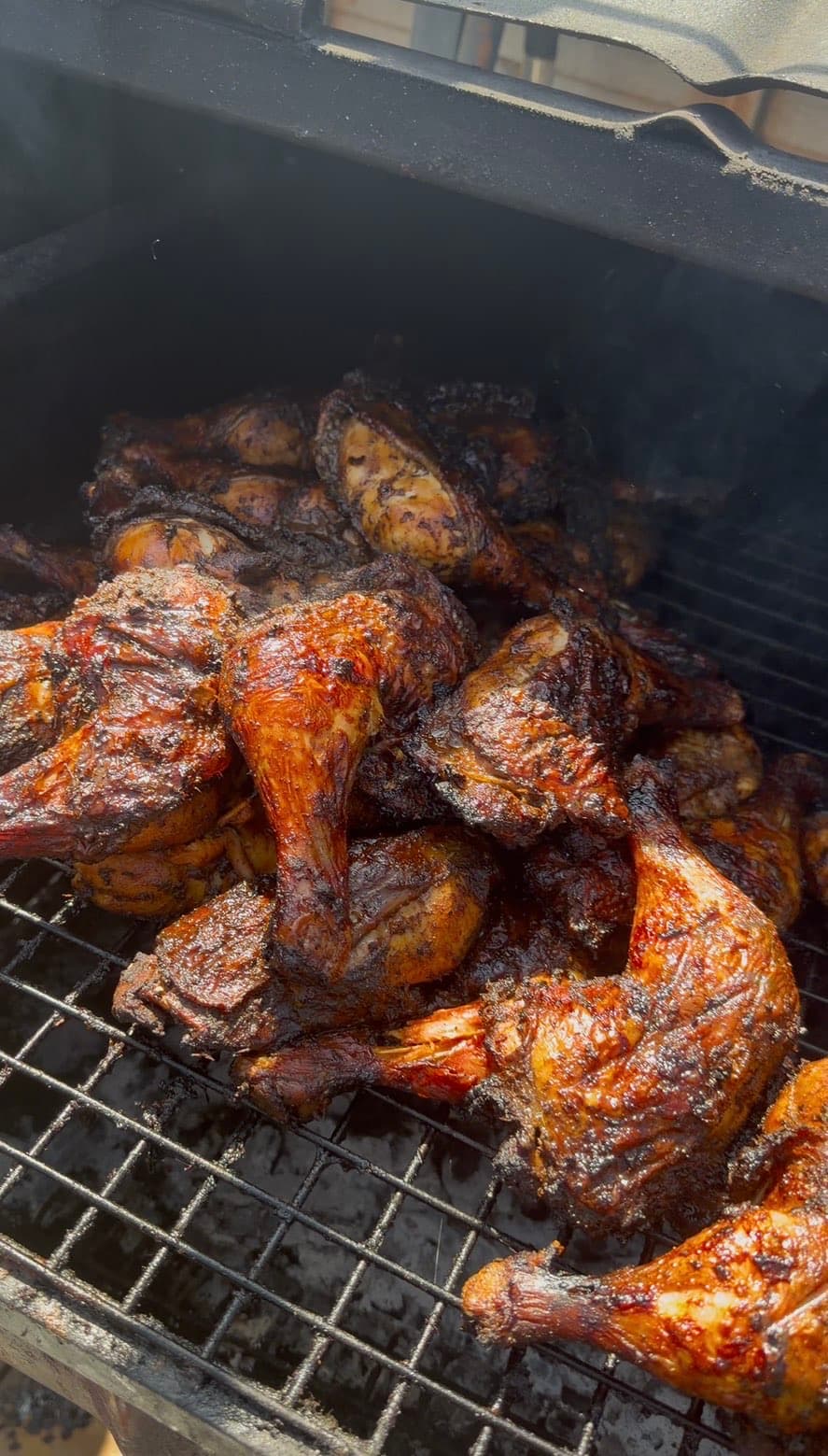 Jerk chicken legs smoking on the charcoal grill